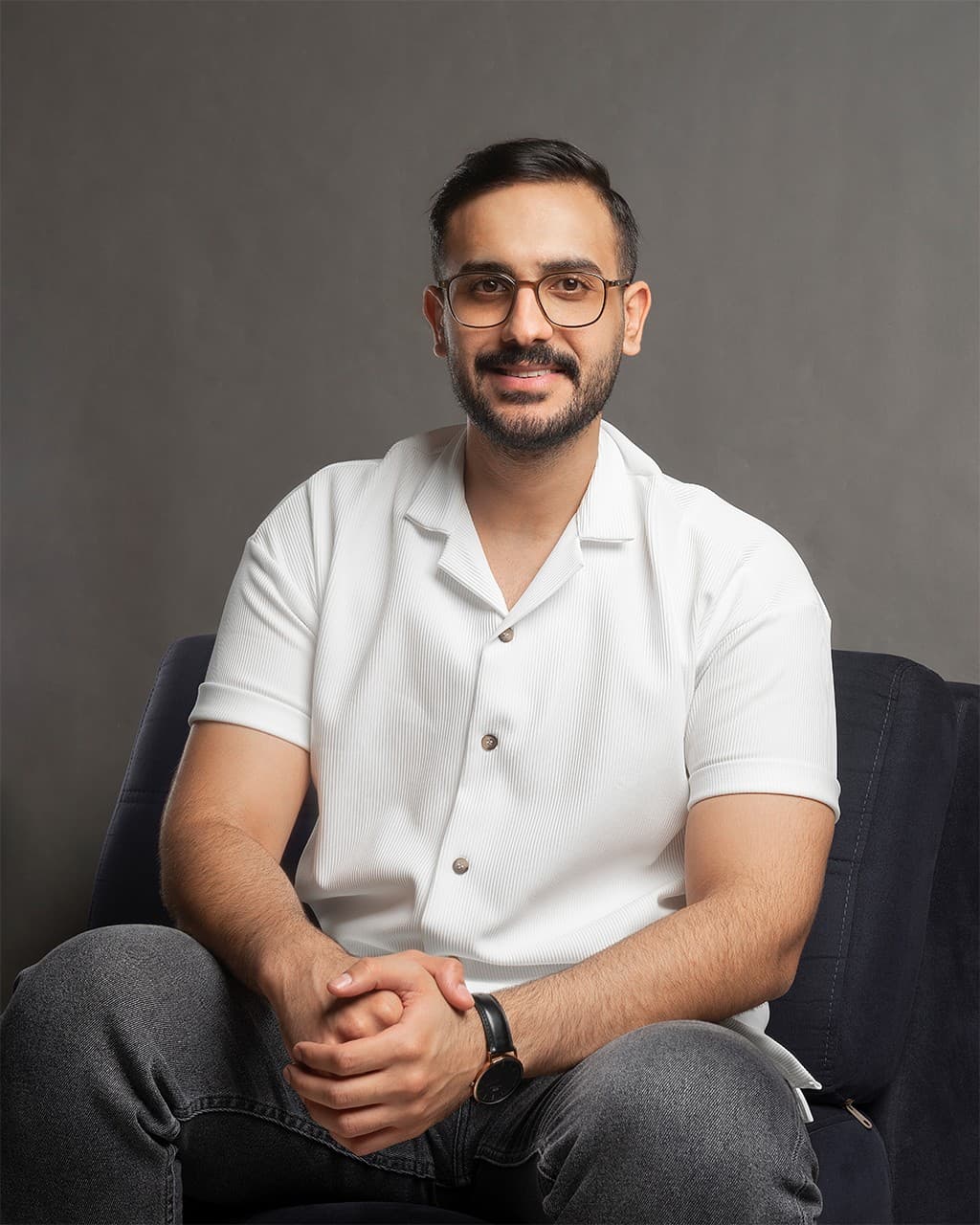 Roozbeh Monfared sitting on a sofa, smiling